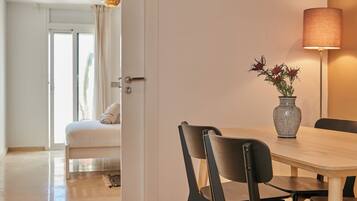 Un coin repas avec une table en bois, deux chaises, un vase de fleurs et un lampadaire.