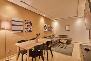 A modern living room with a dining area, featuring a sofa, a coffee table, and a TV.