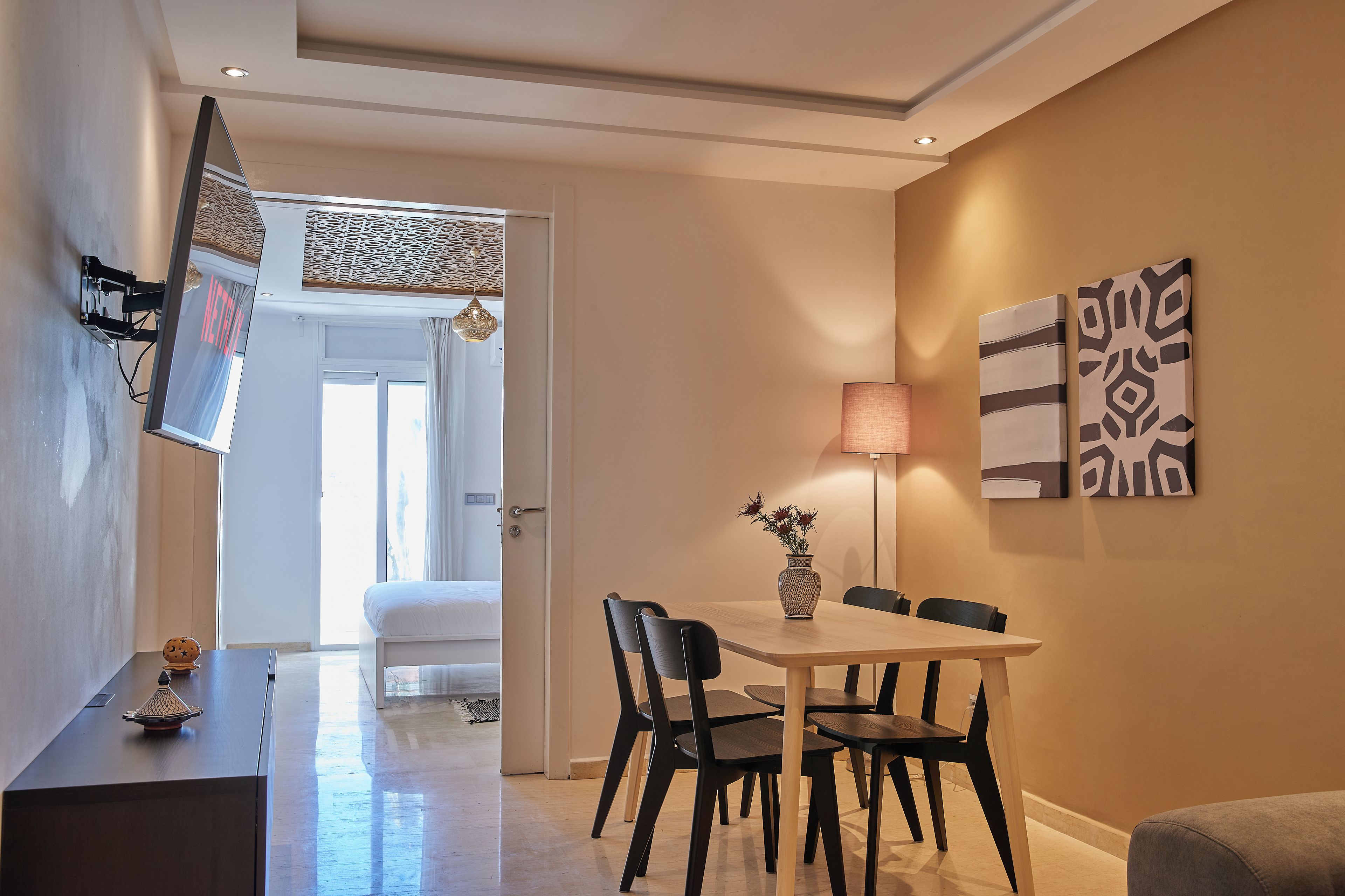 A modern dining area with a table, chairs, and a vase of flowers.