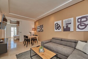 A modern living room with a grey sofa, a coffee table with a plant, and abstract wall art. - Stayhere Rabat - Hassan Heritage (Rabat)
