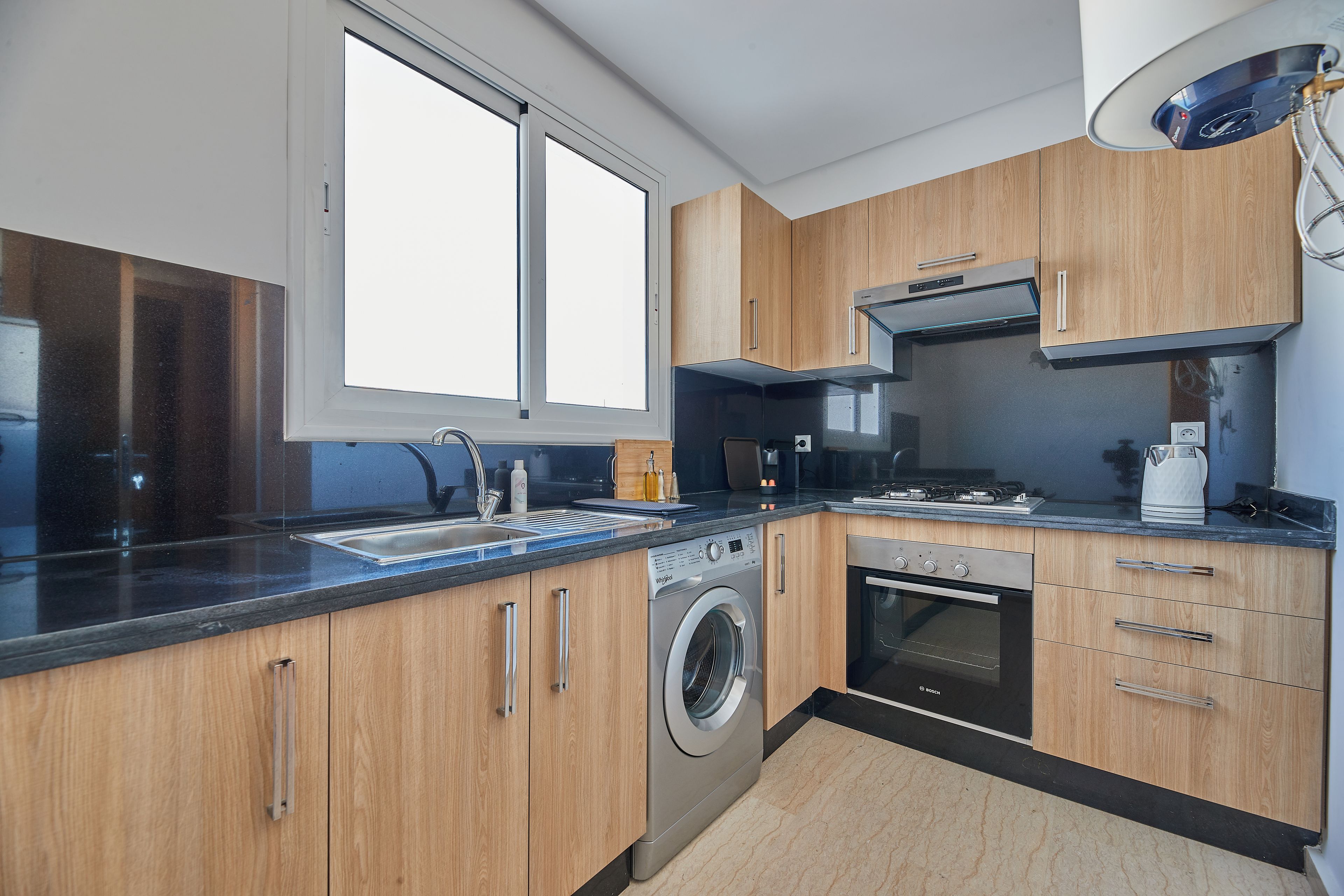 A modern kitchen with wooden cabinets, a built-in washing machine, and a Bosch oven.