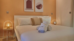 A neatly made bed with white linens, two pillows, and a rolled towel. There are two wall-mounted light fixtures on either side of the bed. - Stayhere Rabat - Hassan Heritage (Rabat)