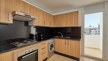 A modern kitchen with wooden cabinets, a Bosch washing machine, and a gas stove.
