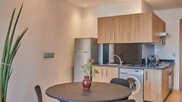 Une cuisine moderne avec des meubles en bois, un lave-linge encastré et un coin repas comprenant une table et des chaises.