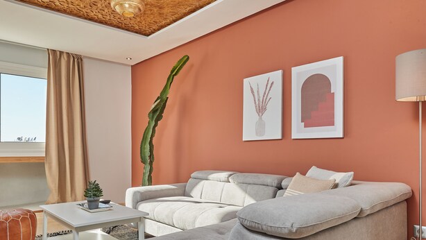 A modern living room with a beige sofa, a white coffee table, and a tall green plant. - Stayhere Rabat - Hassan Heritage (Rabat)
