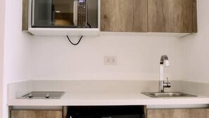 Een keuken met houten kastjes, een magnetron, een vaatwasser en een spoelbak.
