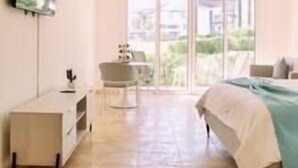 Een slaapkamer met een bed, een bureau, een stoel en een televisie aan de muur.