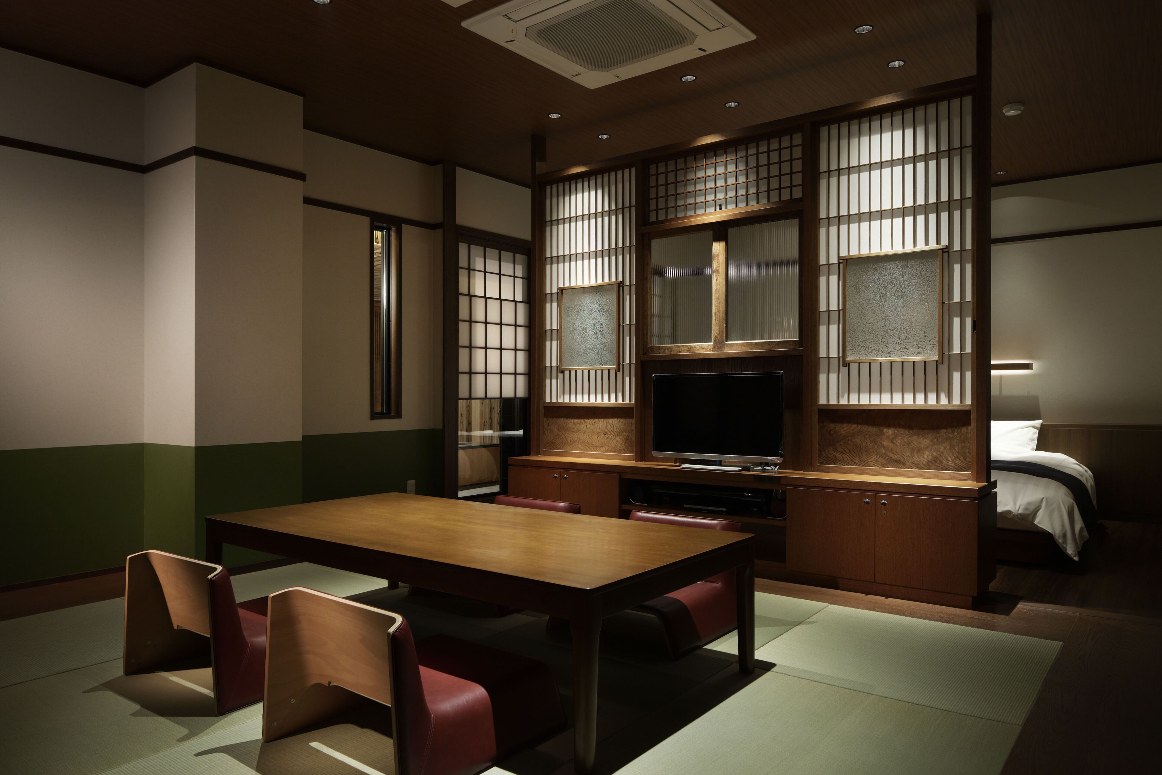 A traditional Japanese-style room with tatami flooring, a low wooden table, and red cushions.