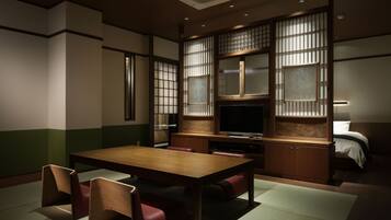 A traditional Japanese-style room with tatami flooring, a low wooden table, and red cushions.