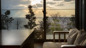 A room with a view of the sea, a wooden table, and a sofa.
