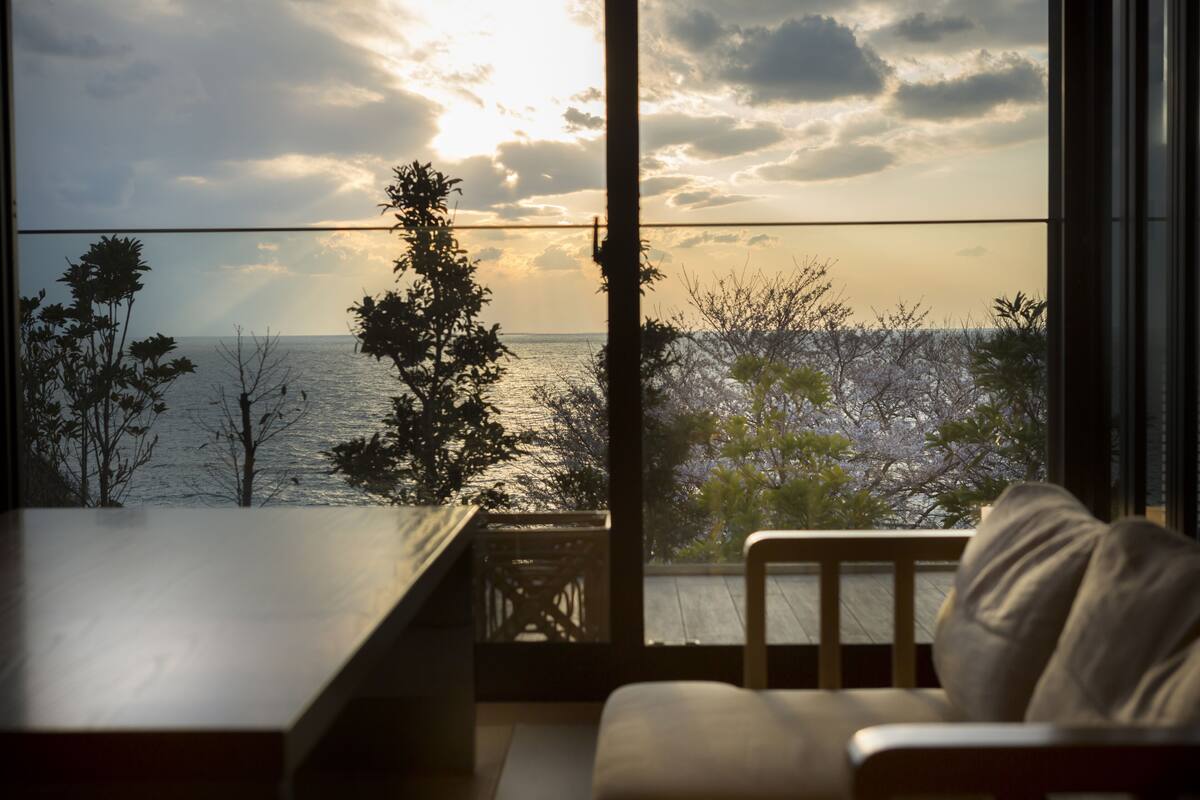 A room with a view of the sea, a wooden table, and a sofa.