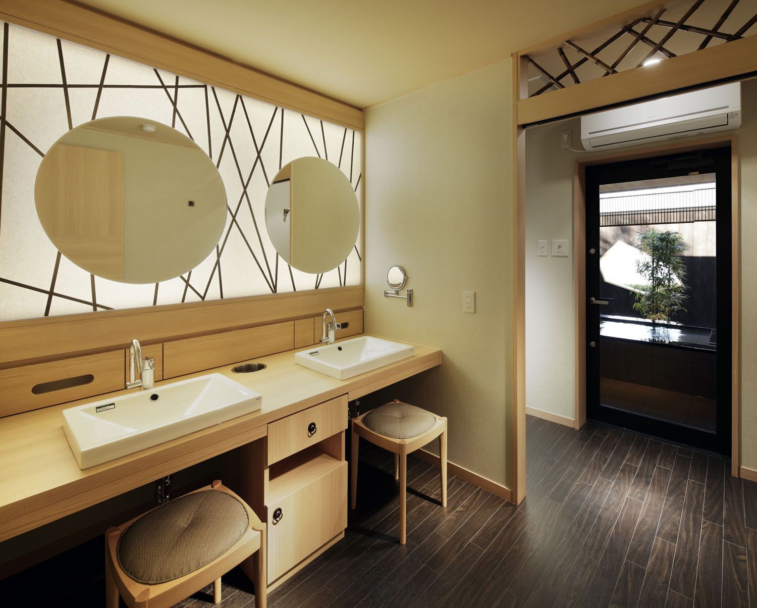 Een moderne badkamer met twee wastafels, een grote spiegel en een klein krukje.