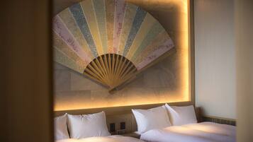 A hotel room with two beds, a large decorative fan, and a wall-mounted clock.