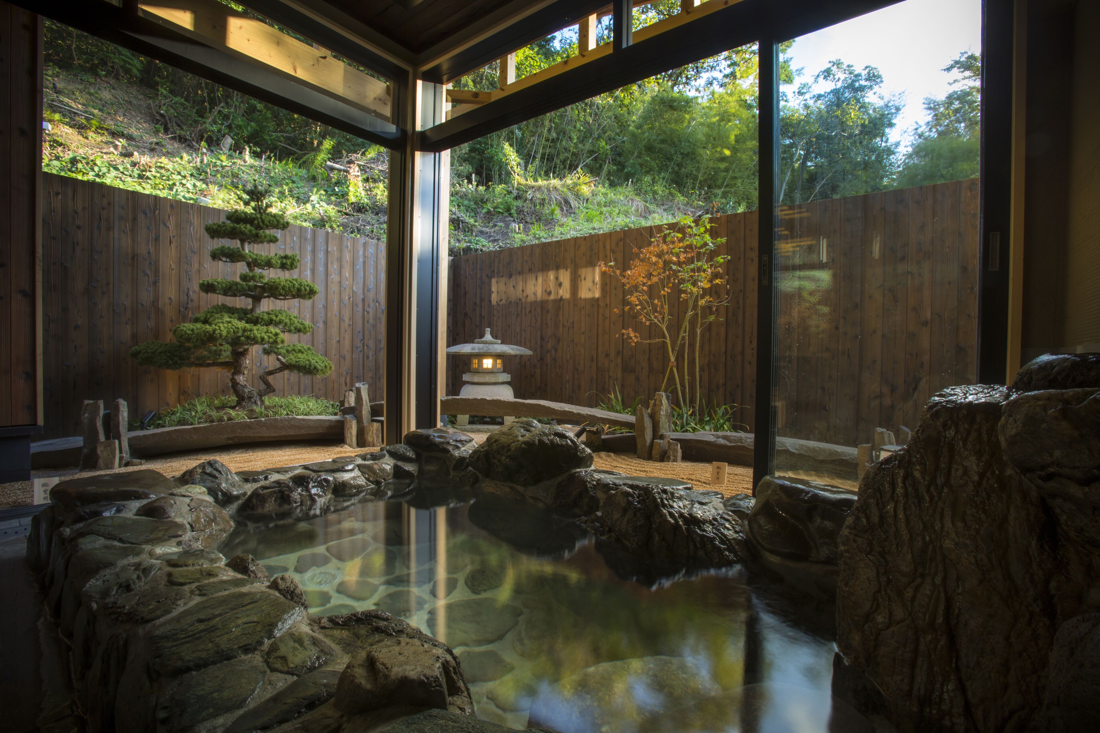 Un giardino tradizionale giapponese con stagno per carpe koi, recinzione in legno e un lanterne.
