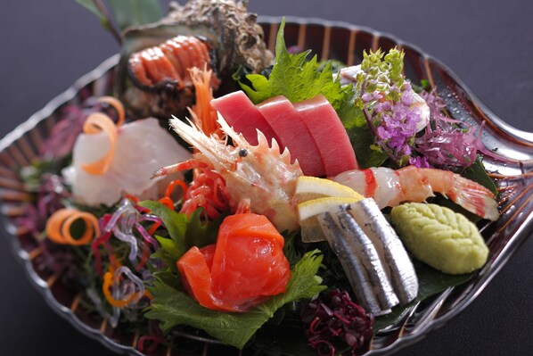 Variedad de sushi y sashimi sobre un plato de metal.
