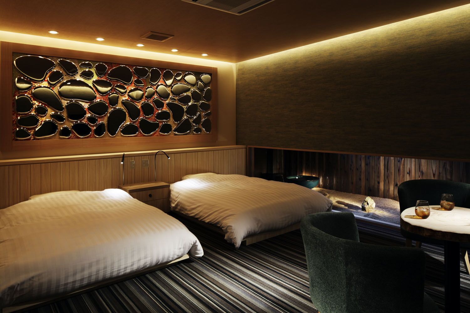 Ein Hotelzimmer mit zwei Betten, einer Sitzecke mit Tisch und einer Wand mit Spiegeln.
