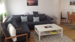 Ein Wohnzimmer mit einem dunkelgrauen Sofa, einem weißen Couchtisch und einem Gemälde an der Wand.