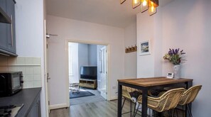 Une cuisine moderne équipée d’un four à micro-ondes, d’une table à manger et de chaises en osier.