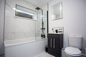 A modern bathroom with a glass-enclosed shower, a white toilet, and a black cabinet with a mirror above it. - Heart of South Shields Modern Interior 2 Bed Flat (South Tyneside)