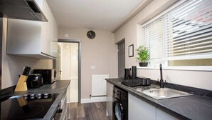 A modern kitchen with a stove, sink, and washing machine.