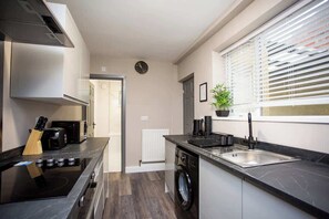 A modern kitchen with a stove, sink, and washing machine. - Heart of South Shields Modern Interior 2 Bed Flat (South Tyneside)