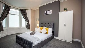 A bedroom with a large bed, a wardrobe, and a window with curtains.