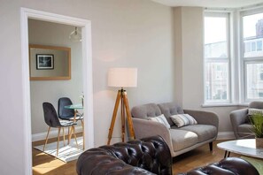 A living room with a sofa, a coffee table, a lamp, and a tripod.