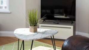 A living room with a marble table, a potted plant, a flat-screen TV, and a leather couch. - Whitey Bay Coastal Bliss (Whitley Bay)