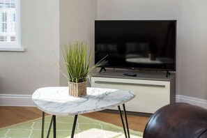 A living room with a marble table, a potted plant, a flat-screen TV, and a leather couch. - Whitey Bay Coastal Bliss (Whitley Bay)