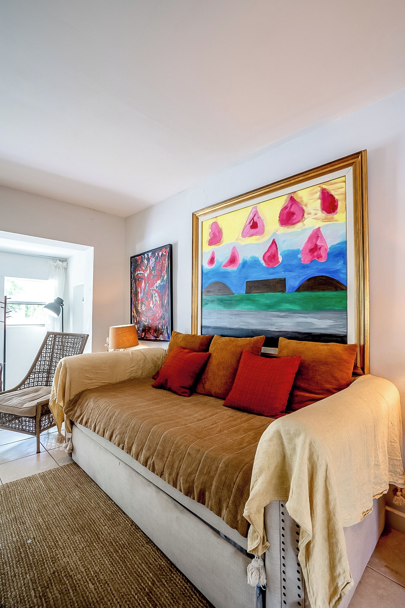 Een slaapkamer met een groot bed, een schilderij aan de muur en een stoel bij het raam.