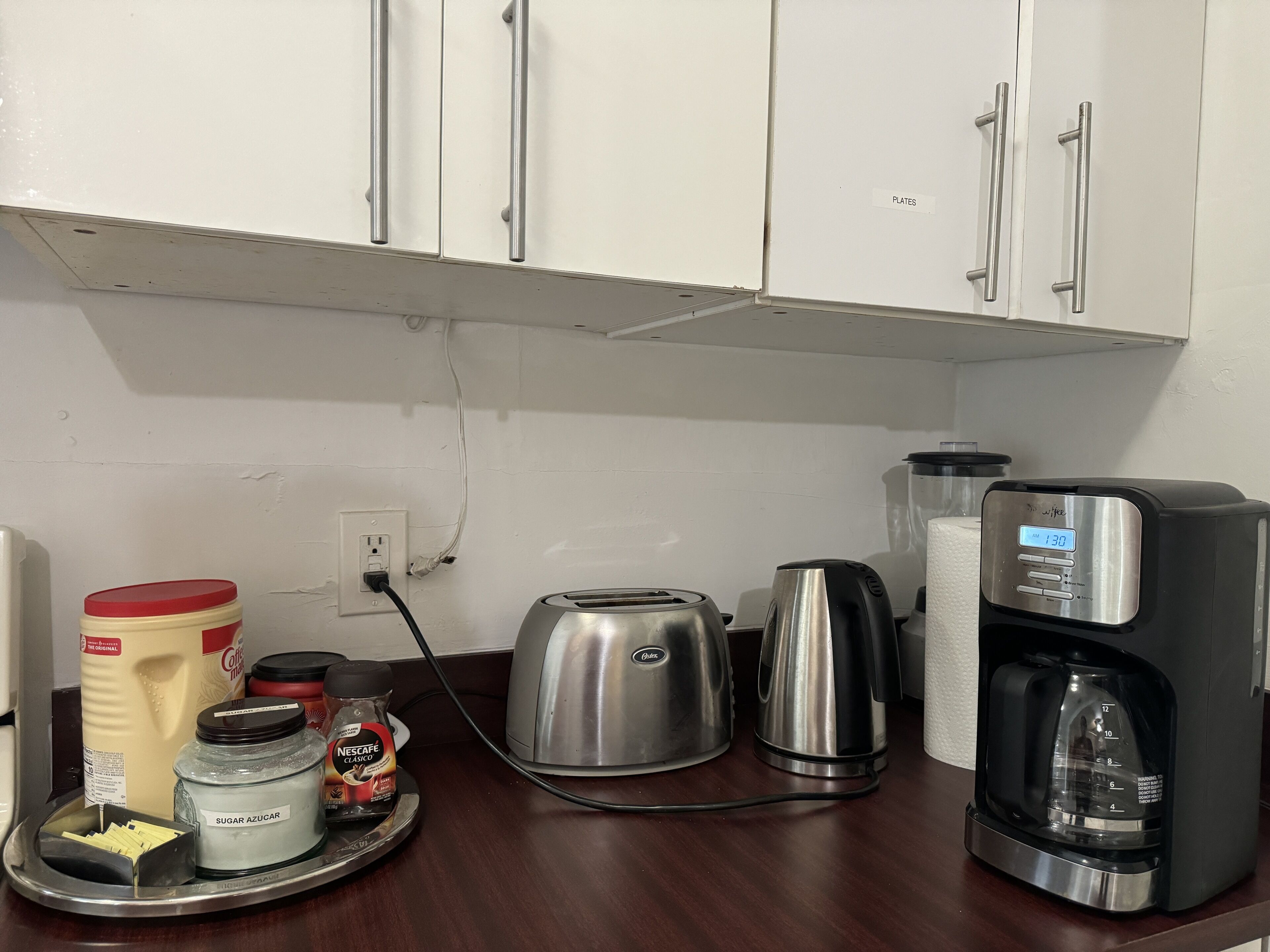 Un plan de travail de cuisine avec une machine à café, un grille-pain et un récipient à sucre.