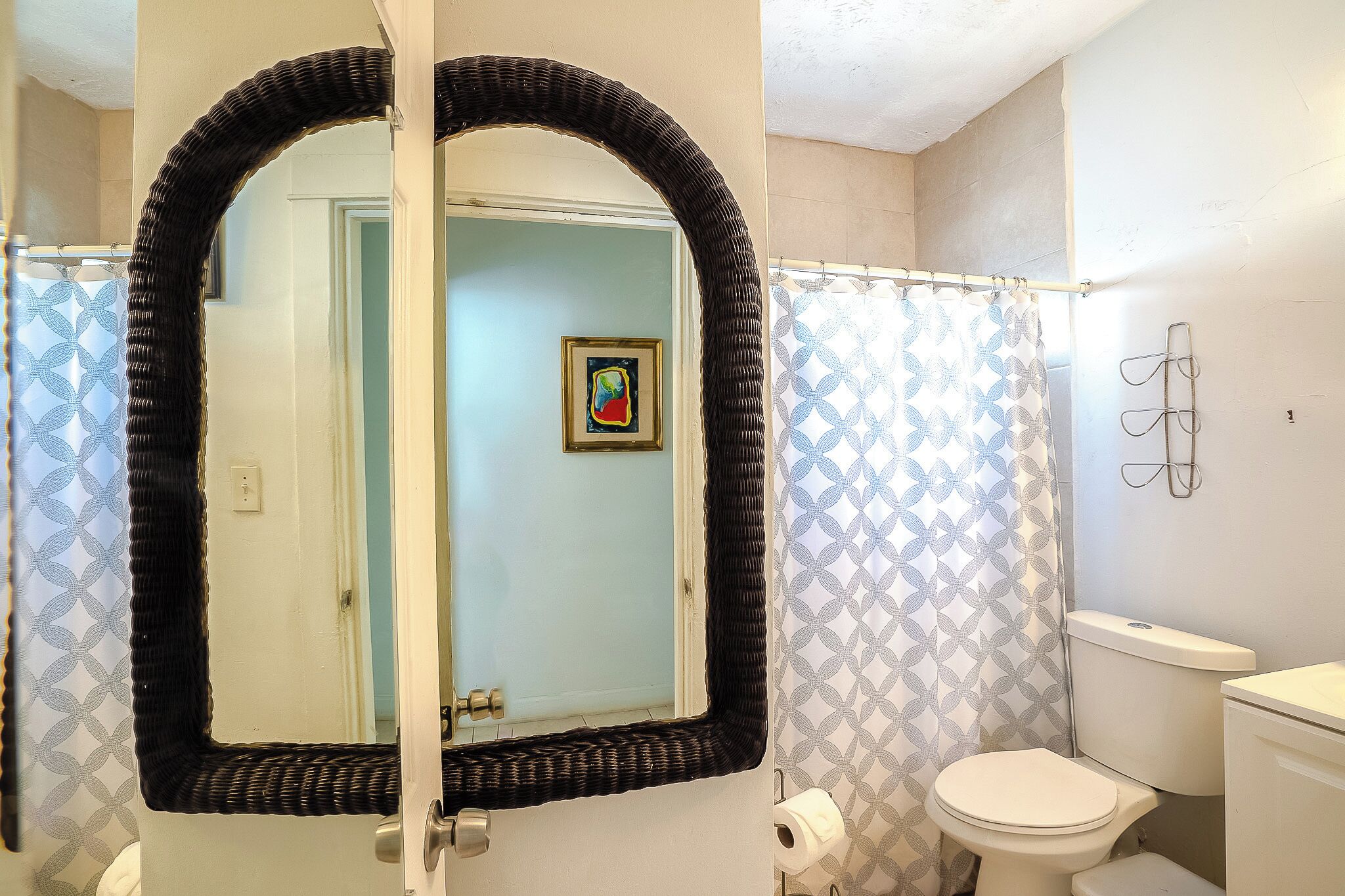 Une salle de bain avec un grand miroir, des toilettes et un rideau de douche.
