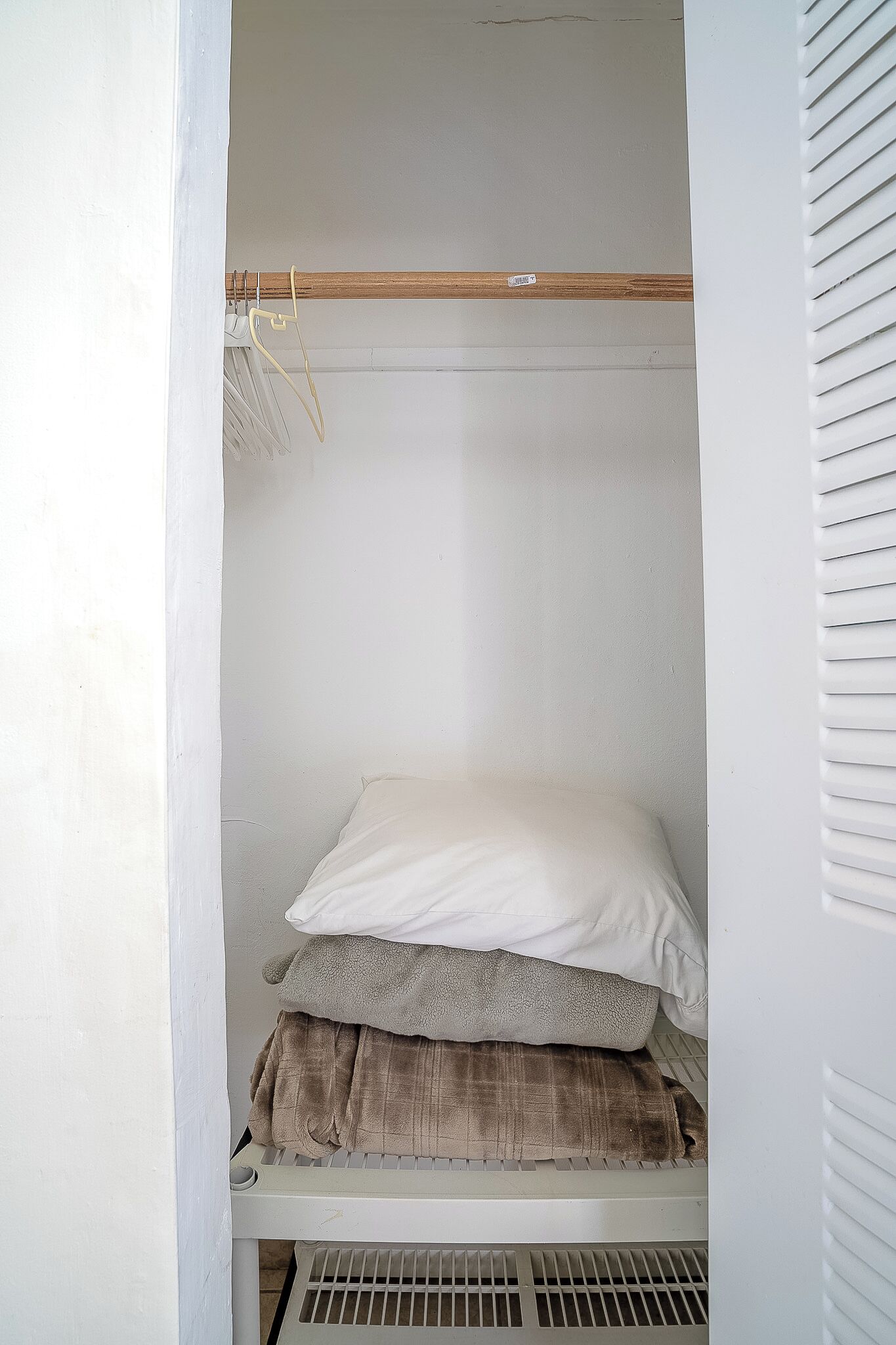 A white closet with a wooden shelf at the top and a white mattress at the bottom.