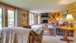 Interior acogedor de una cabaña de madera con chimenea, televisor, sofá y cama.