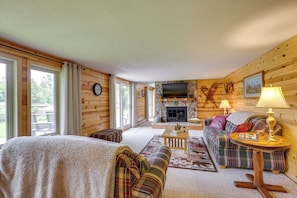 A cozy log cabin interior with a fireplace, a television, a sofa, and a bed.