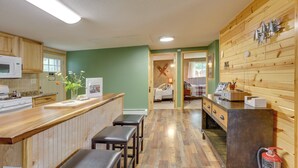 Una cocina con gabinetes de madera, microondas y una barra de madera con taburetes.