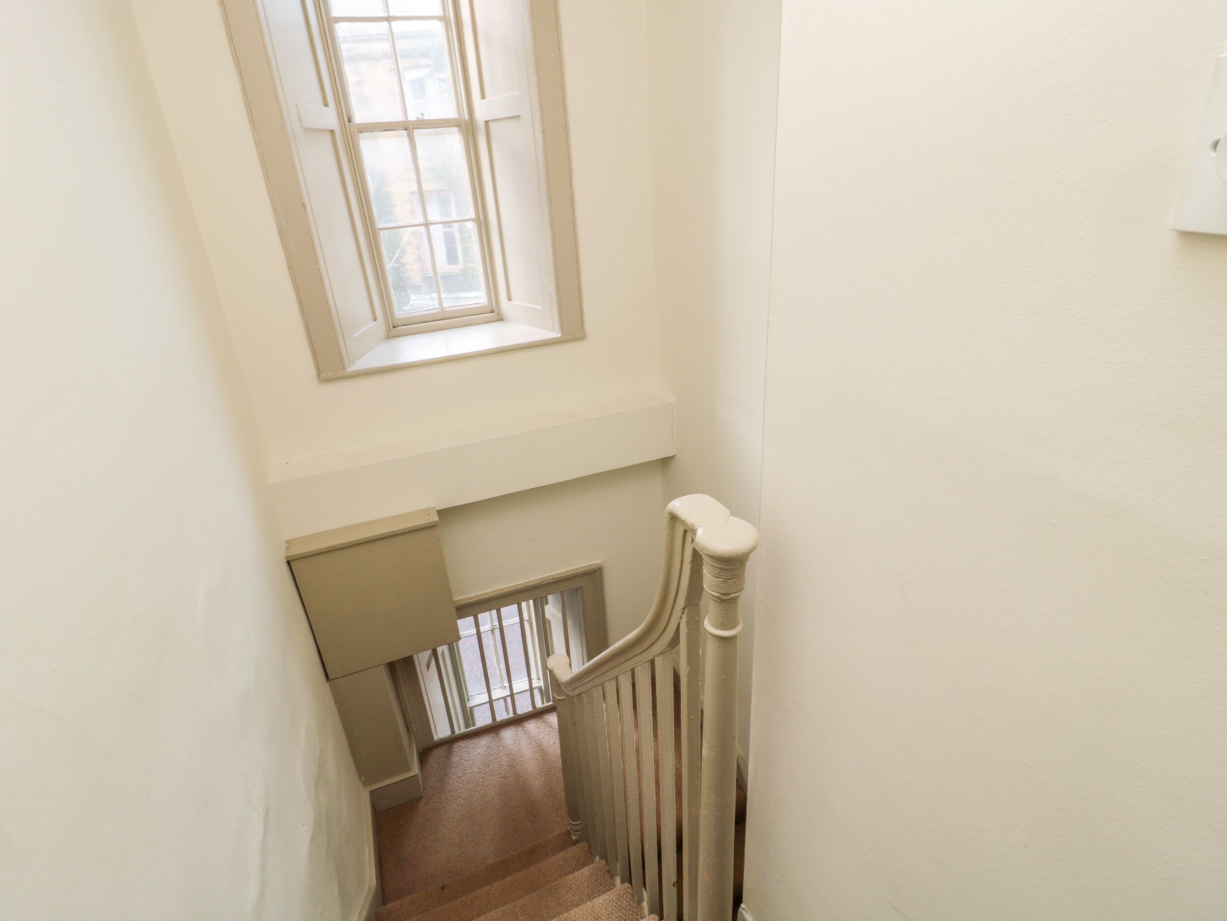 A staircase with a white railing and a window above it.