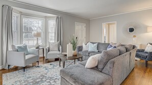 A living room with a grey sofa, armchairs, a coffee table, and a patterned rug. - Home in sought after centrally located Lindley Park neighborhood. (Greensboro)