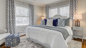 A bedroom with a large bed, two bedside tables, a ceiling fan, and patterned curtains. - Home in sought after centrally located Lindley Park neighborhood. (Greensboro)