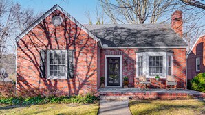 A brick house with a gabled roof, a front porch with a bench, and a small garden area. - Home in sought after centrally located Lindley Park neighborhood. (Greensboro)