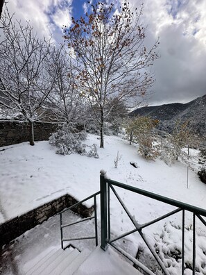 A snow-covered outdoor area with a stone wall and a metal railing.