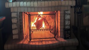 Una chimenea con repisa rústica y fuego encendido en su interior.