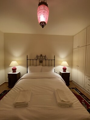 A neatly made bed with pillows, two bedside tables with lamps, a hanging light fixture, and a wardrobe. - Kalavryta Villa Nano 360 view with fireplace  (KALAVRITA)