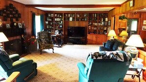 A cozy living room with a fireplace, a television, and a bookshelf filled with books and framed photos. - Lake Charles #1 Rental located close to everything. Casino's/mall/restaurants.  (Lake Charles)