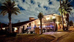 A two-story building with a brick facade, a balcony on the second floor, and a fenced front yard with palm trees. - Lake Charles #1 Rental located close to everything. Casino's/mall/restaurants.  (Lake Charles)