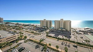 A coastal hotel with multiple high-rise buildings, a parking lot, and a view of the beach.