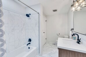 Un bagno moderno con vasca, doccia e lavandino.