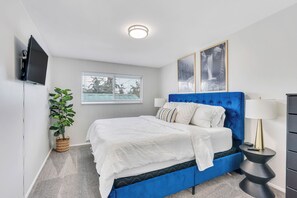 Una camera da letto con un letto, una televisione, una finestra e una pianta.