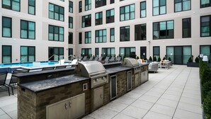 A rooftop pool area with a barbecue setup and lounge chairs. - Luxury Living in OTR:1-BR Oasis With Free Parking+Pool+Gym (Cincinnati)