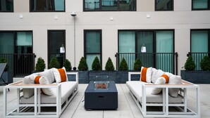 A modern outdoor seating area with two white sofas and a central coffee table. - Luxury Living in OTR:1-BR Oasis With Free Parking+Pool+Gym (Cincinnati)